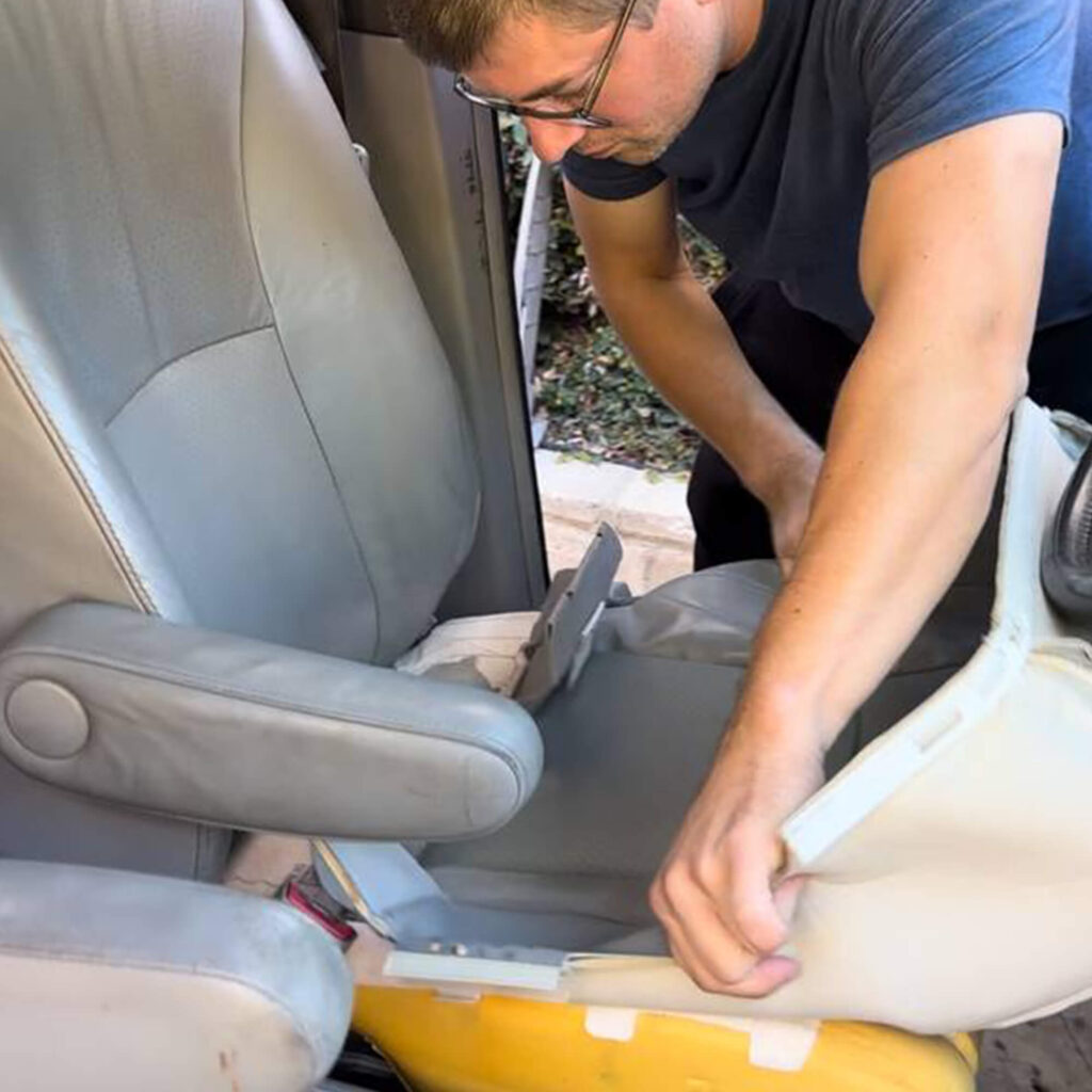 Technician reinstalling a repaired car leather seat cover