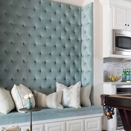 Custom tufted upholstered wall panels with integrated bench seating in a residential kitchen interior