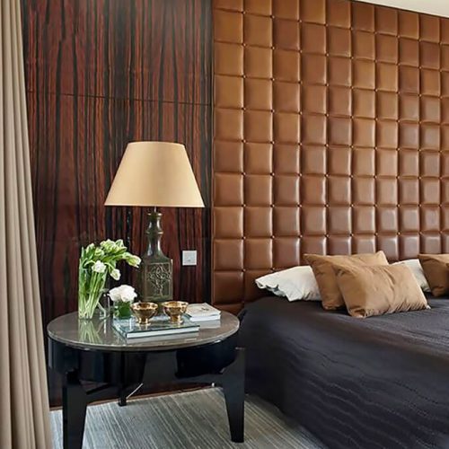 Square leather upholstered wall panels forming a feature wall behind a bed